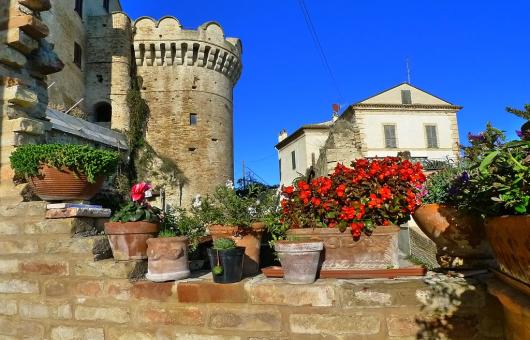 Castello medievale con fiori in vaso e cielo blu.