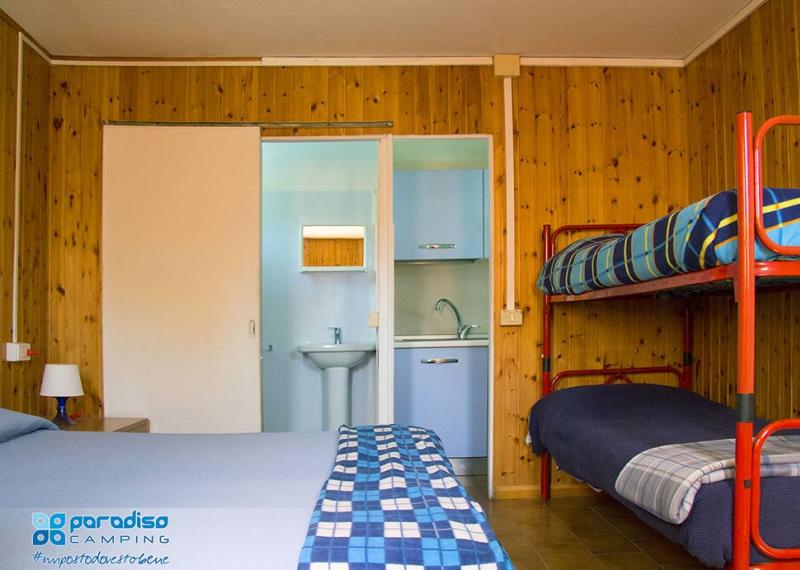 Camera con letto matrimoniale, letti a castello e bagno privato in campeggio.