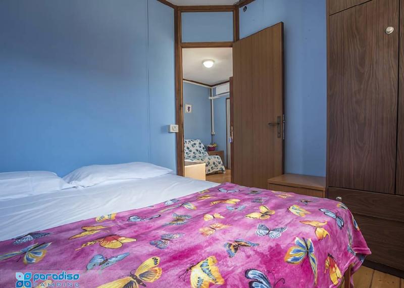 Camera da letto con coperta a farfalle, pareti blu e armadio in legno.