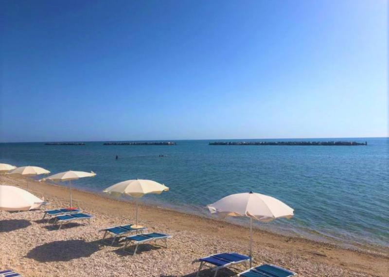 Spiaggia tranquilla con ombrelloni bianchi e mare calmo.