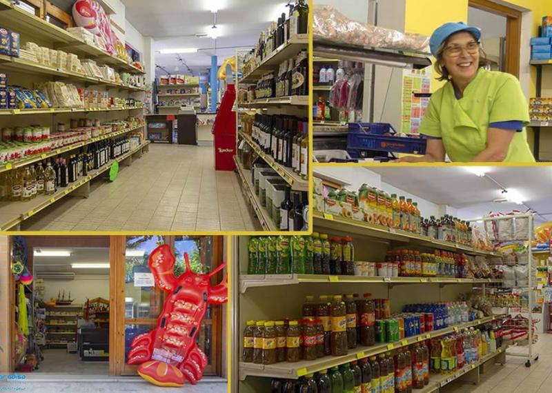 Negozio di alimentari con scaffali pieni e una commessa sorridente.